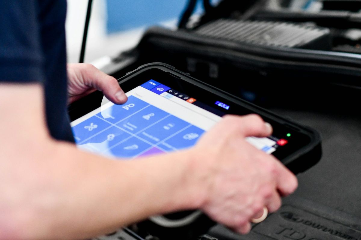 Técnico usando tablet de diagnóstico eletrônico na oficina