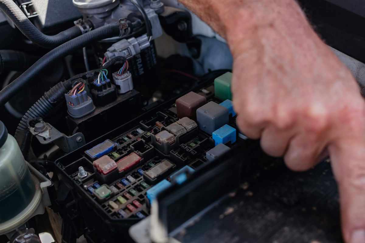 Técnico verificando a caixa de fusíveis e relés do sistema elétrico