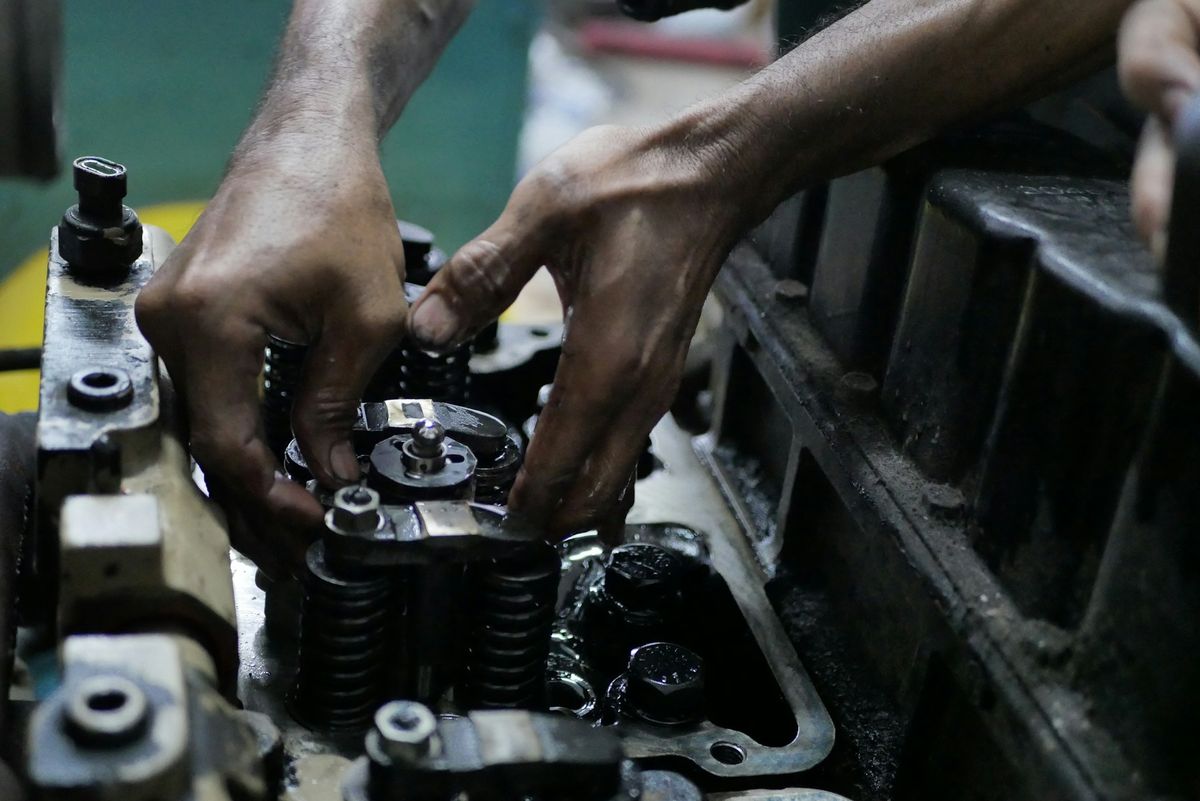 Mecânico ajustando as válvulas de um motor diesel aberto
